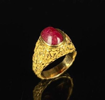 a close up of a gold ring with a red stone