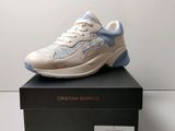 Les baskets blanches et bleues sont posées sur une boîte noire