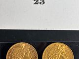 two gold coins in a black box with a white background