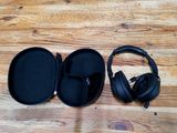 un casque audio posé dans son étui sur un plancher en bois