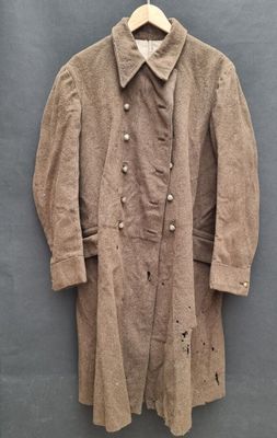 un vieux manteau accroché au mur avec un cintre en bois