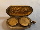a silver case with two small gold objects inside of it