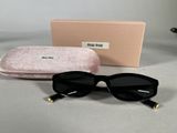 black sunglasses with gold accents and a pink case on a table