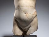 une image représentant une statue d'un homme nu posée sur un socle en bois