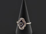 une image représentant une bague posée sur un cône noir, sur fond noir
