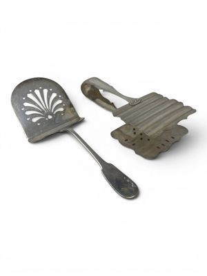 two metal utensils sitting next to each other on a white surface