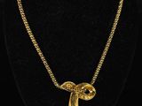 a gold plated necklace with a bird shaped pendant on a black mannequin
