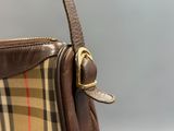 the brown and tan plaid purse has a gold buckle on it