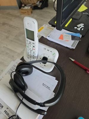 un téléphone portable et des écouteurs posés sur un bureau, à côté d'un ordinateur