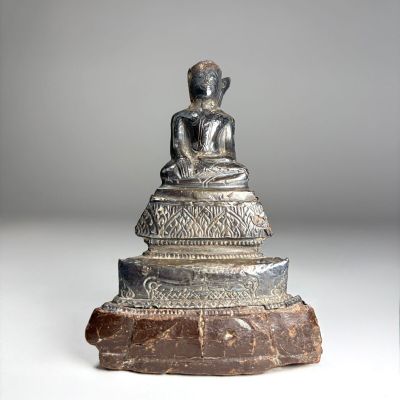 une image représentant une statue d'une personne assise sur un rocher