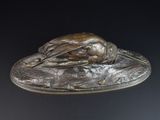 une statue en bronze représentant un oiseau posée sur un plateau