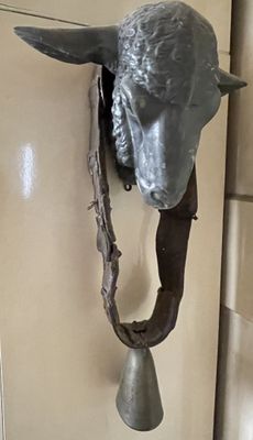 une statue représentant un mouton avec une cloche attachée à la tête