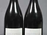 two bottles of red wine sitting next to each other on a table