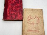 an old book sitting on top of a white table next to a red book