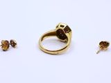 two gold rings and a pair of earrings on a white surface
