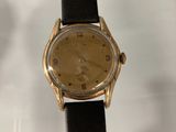 an image of a gold wrist watch on a black leather strap