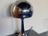 une lampe argentée brillante posée sur une table noire à côté d'un miroir