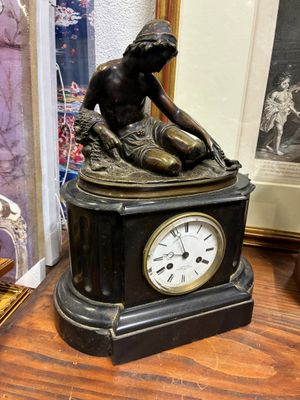 une statue d'un homme assis au sommet d'une horloge