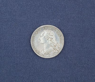 un gros plan d'une pièce d'argent posée sur un tissu bleu