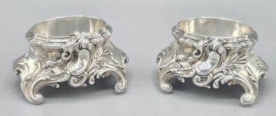 two silver vases sitting on a table next to each other