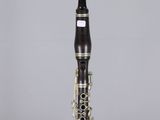 a close up of a clarinet on a clear surface with a gray background