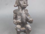 statue représentant un homme assis sur une chaise, coiffé d'un chapeau