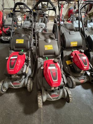 Plusieurs tondeuses à gazon sont alignées en rang dans un garage