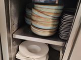 many plates and bowls stacked on a shelf in the kitchen