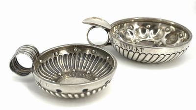 two silver metal bowls with handles on a white surface
