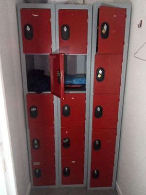 Plusieurs casiers rouges se trouvent dans une petite pièce dont la porte est ouverte.