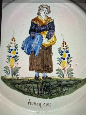 une assiette sur laquelle est représentée une femme tenant un sac bleu