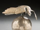 a silver bird sitting on top of a silver ball
