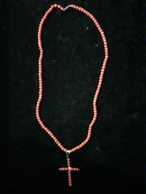 a red beaded necklace with a cross on it