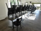 Des tables et des chaises sont alignées dans une grande pièce dotée de fenêtres