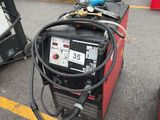 deux machines à souder sur un parking, avec d'autres équipements en arrière-plan