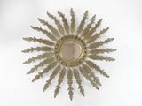 a gold sunburst on a white surface with a mirror