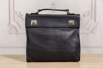 black leather briefcase sitting on top of a wooden table next to a wall