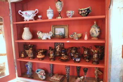 a red bookcase with many different vases on it