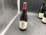 three bottles of wine sitting on a counter in front of a microwave