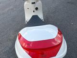 un scooter rouge et blanc garé sur le bord de la route