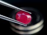 un gros plan sur une paire de pinces tenant une pierre rouge