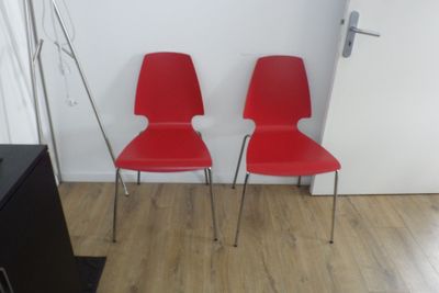deux chaises rouges placées l'une à côté de l'autre sur un parquet en bois massif