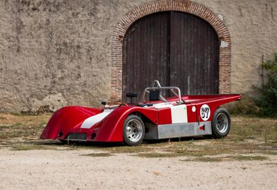 une voiture de course rouge et blanche garée devant un immeuble