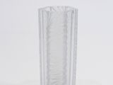 un vase en verre transparent posé sur une surface blanche