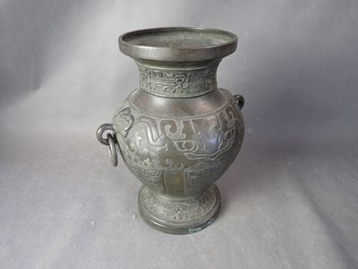 un vase en argent posé sur une surface blanche