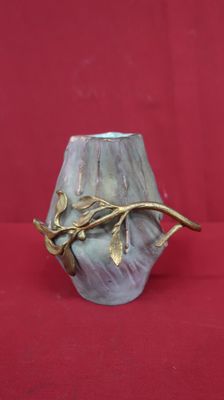 un vase orné d'une branche, posé sur une surface rouge
