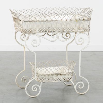 an image of a white metal baby crib with a basket on it