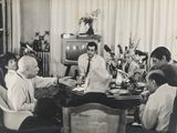 many people sitting around a table eating together