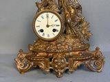 une horloge en or posée sur une table à côté d'une paire de ciseaux