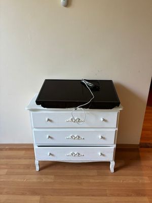 une commode blanche sur laquelle est posé un ordinateur portable